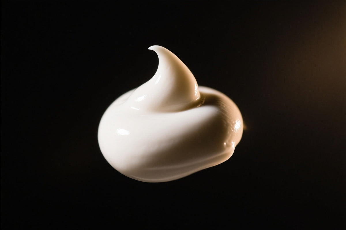 A dollop of white cream with a curled peak on a dark background