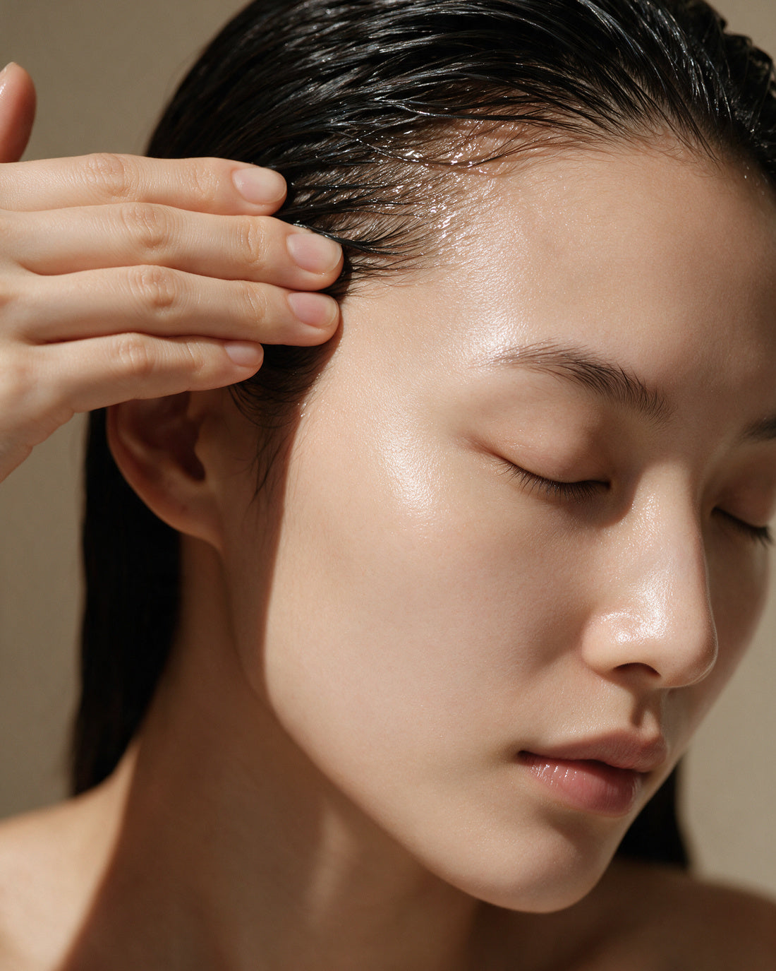 Editorial frame for the HIGH GLOSS SHAMPOO: wet hair drawn straight back with four fingers at the temple.