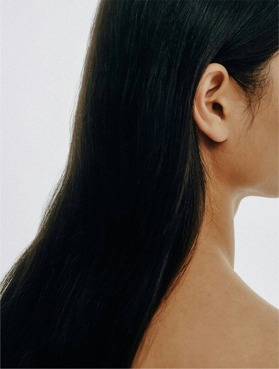 Long dark hair falling across a bare shoulder, KERATIN SHIELD HAIR MIST
