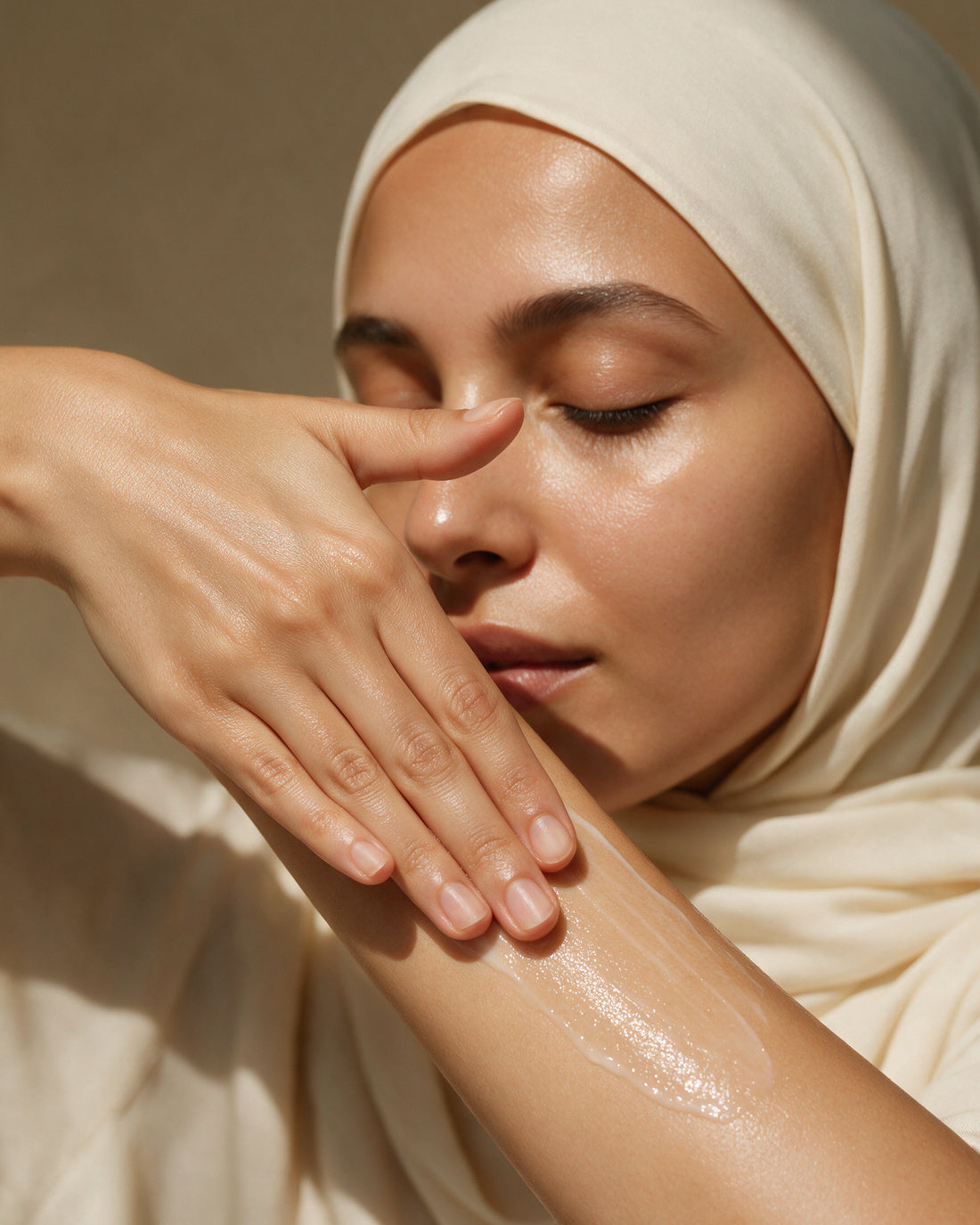 A hand smoothing a sheer lotion along a bare forearm, soft glow